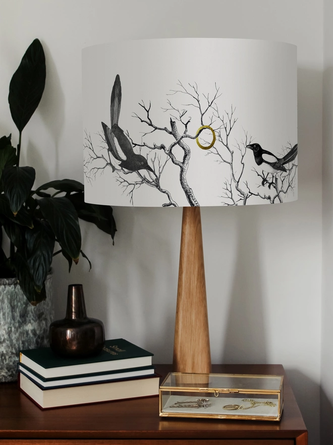 Handmade lampshade featuring cheeky magpies with gleaming gold details, inspired by traditional folklore and whimsical home decor.