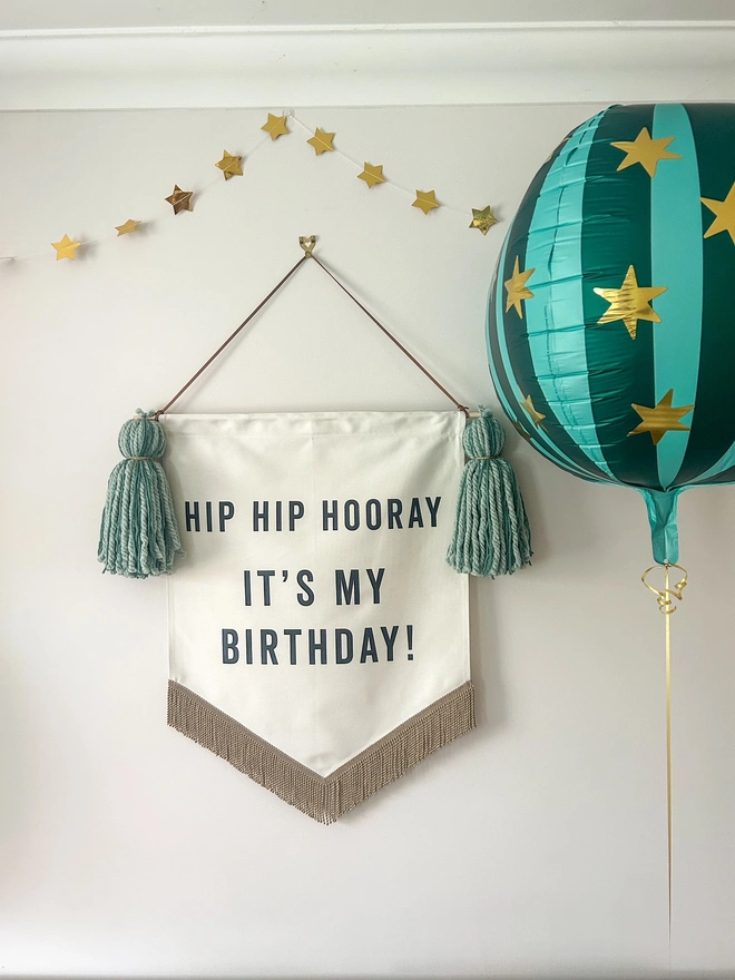 Large handmade birthday banner with green tassels with a round green striped star balloon