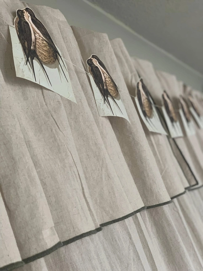 A string of bunting depicting swallows on their nests