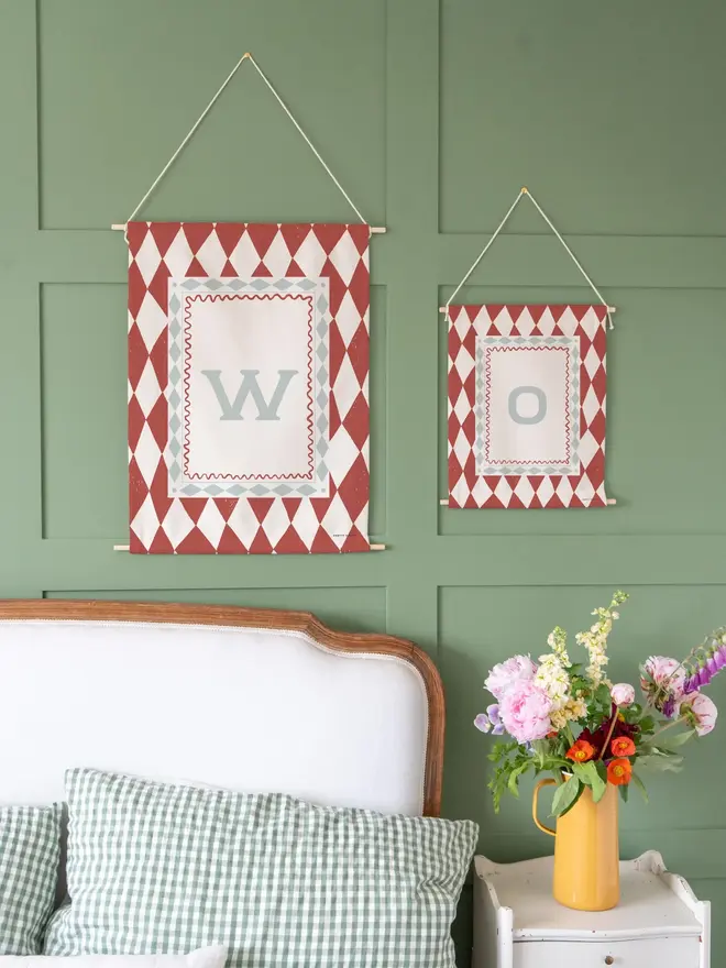 Harlequin Initial Fabric Banner, red mini and midi next to each other against a green wall. 