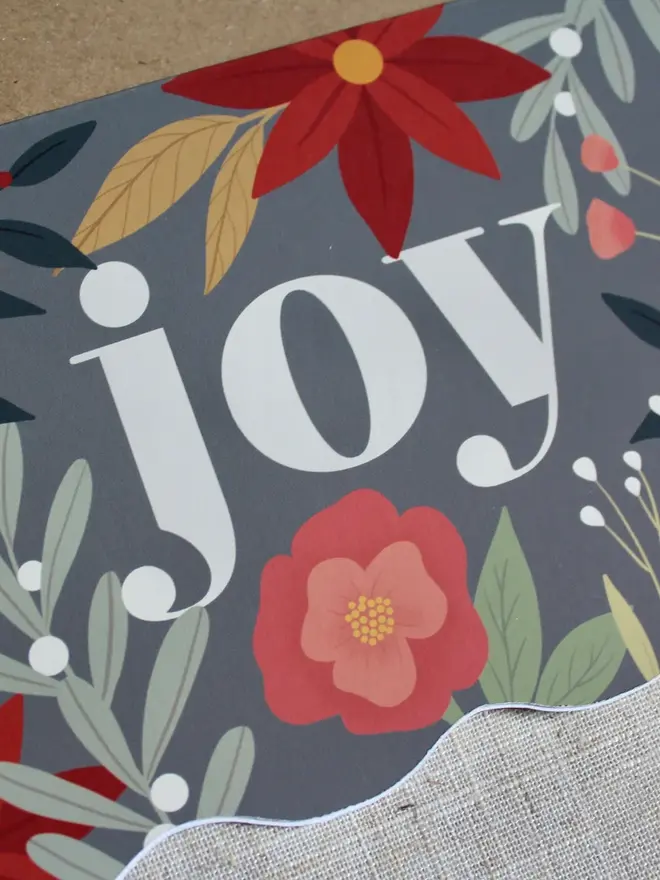 floral joy christmas card. wavy edged card decorated with the word joy and illustrated flowers.