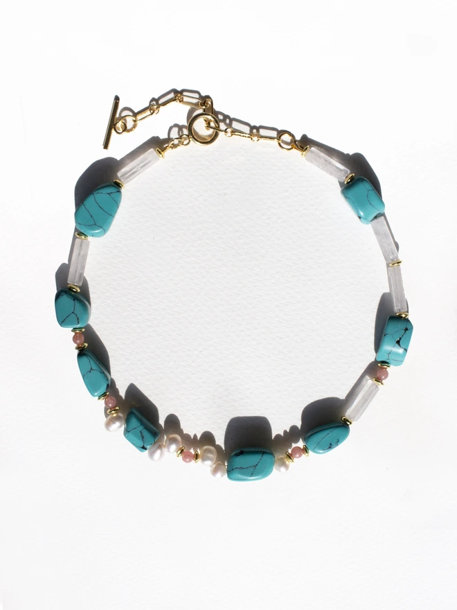 Necklace with turquoise, rose quartz and pearl beads on a white background