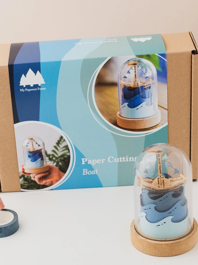 the packaging of a paper craft kit and a paper boat sculpture by My papercut Forest