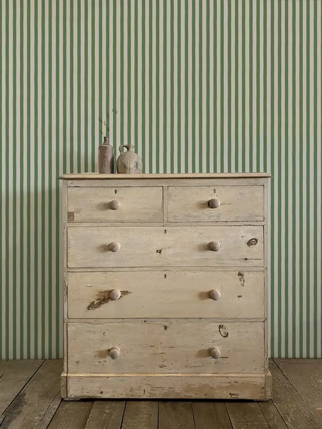 'circus stripe' green wallpaper. a green and beige patterned wallpaper on a wall.