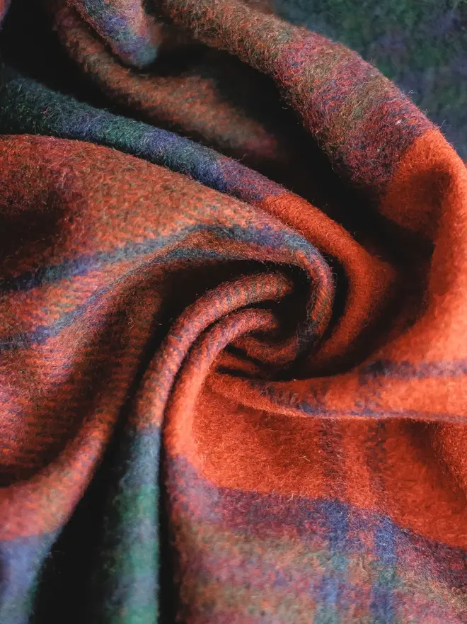 Lindsay Tartan Blanket, a red blanket curled up. 