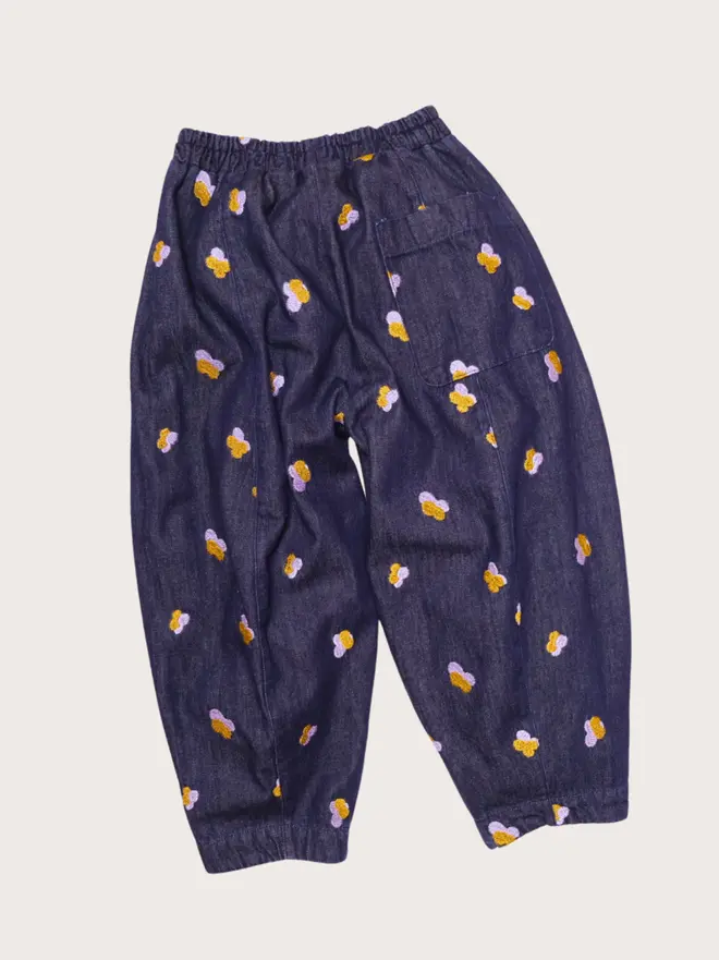 Back flat lay of Studio Koter Manu trousers in Denim Petal, showing the rear patch pocket and embroidered petals.