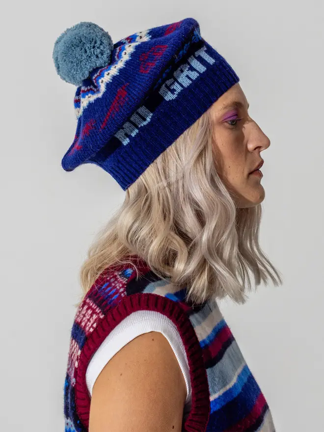 Model wearing the fairisle feminist beret in Klein  featuring the wording No Grit No Pearl