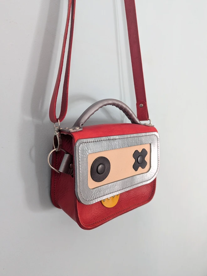 Hanging red leather robot cross body bag, side view.