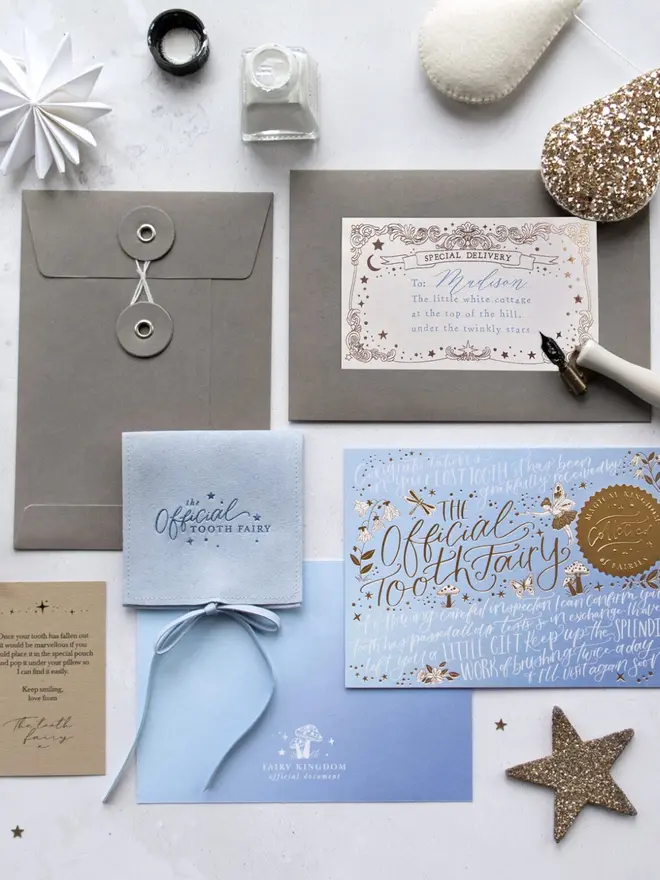 The blue set laid out with grey envelopes, a "Special Delivery" label for Madison and a pale blue pouch. A "Fairy Kingdom official document" card and the Tooth Fairy's note sit alongside.