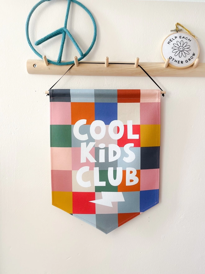 Cool kids club wall banner hanging on a wooden peg rail