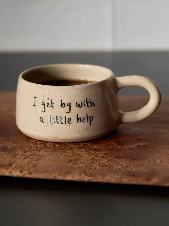Cream ceramic mug with the words 'I Get By With A little Help' written on it 