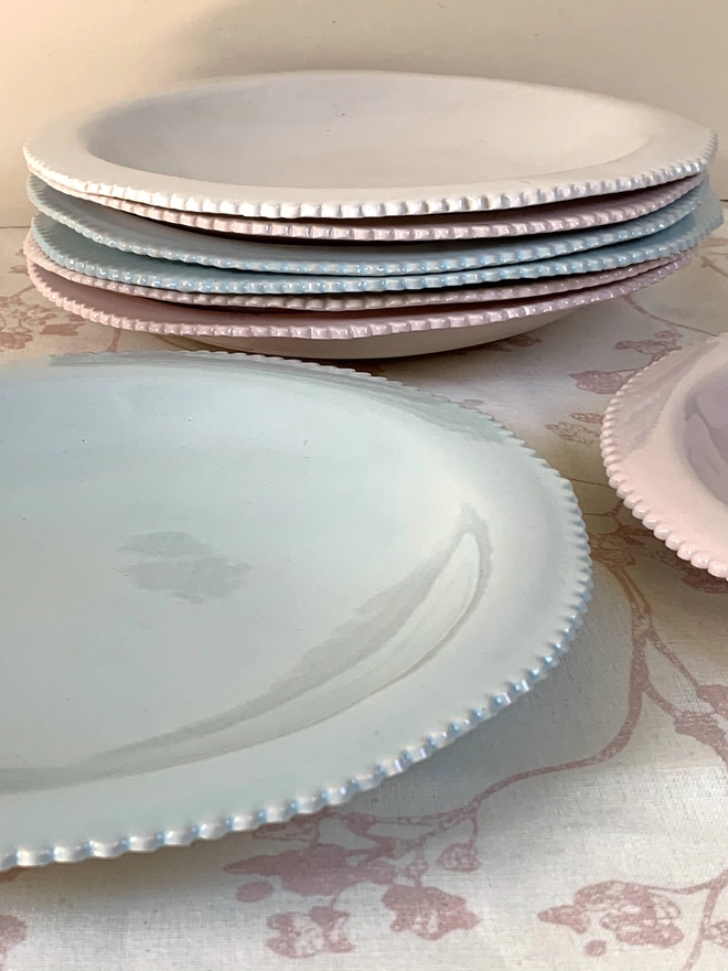 White, pale pink, and soft blue pasta bowls with scalloped edge on flat rim