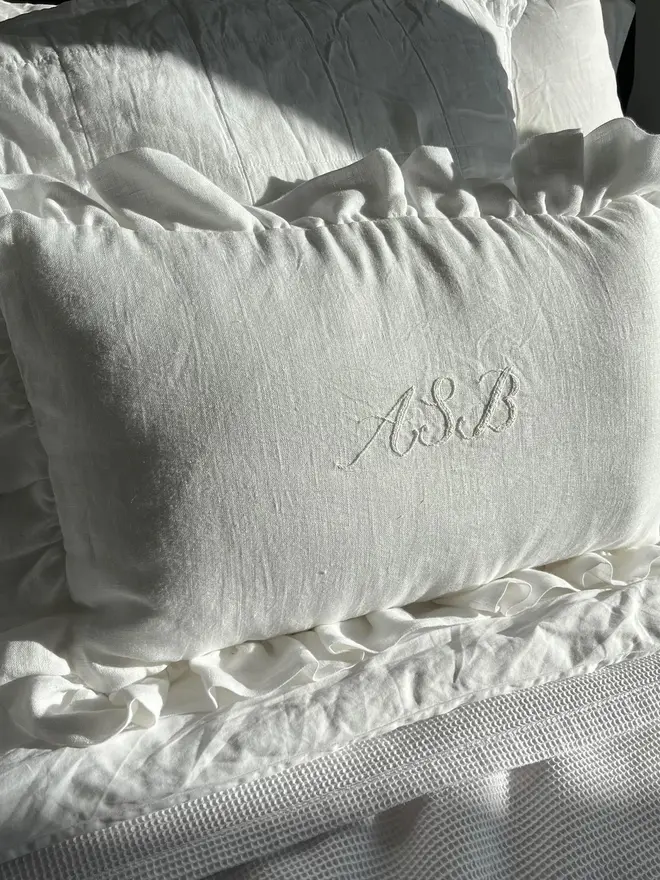 Personalised Handmade Embroidered Linen Cushion With Ruffle, cream cushion on a sofa with a personalised message. 