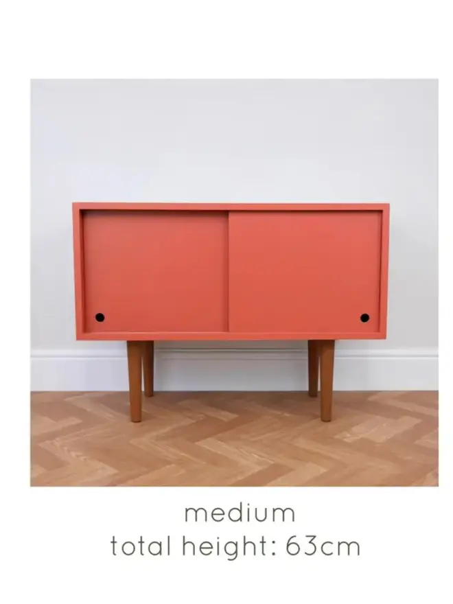 Mid-century cabinet with coral sliding doors and wooden tapered legs.