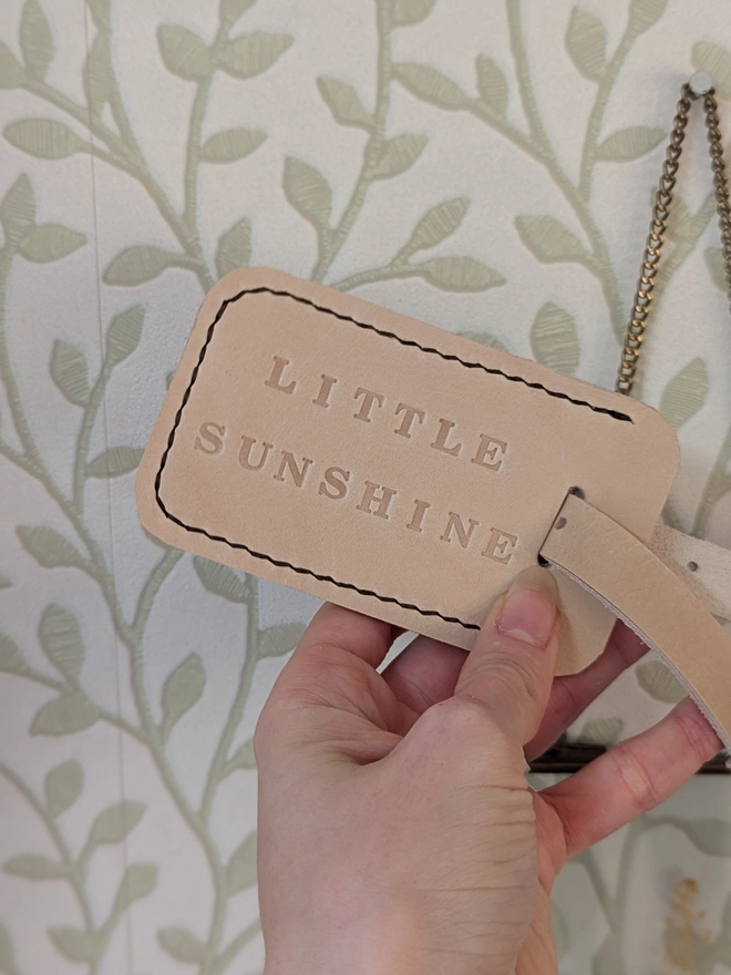 Personalised Leather Luggage Tag. Handmade natural cream leather luggage tag. Personalised with the phrase 'Little Sunshine'. Hand stitched with dark contrasting thread.