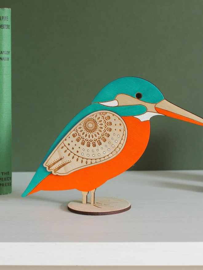 Standing Wooden Kingfisher, orange and blue wooden bird decoration standing on a platform. 