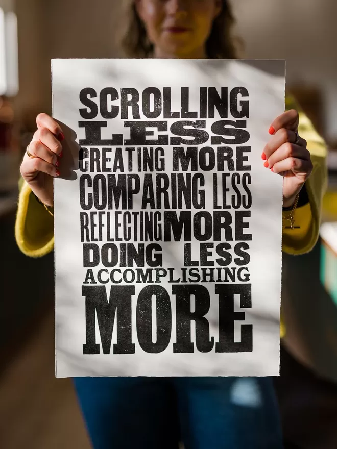 Scrolling Less - Letterpress Poster by the SmallPrint Co seen held by a woman wearing a yellow jacket