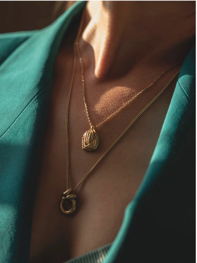 layered gold necklaces worn with an oversized blazer