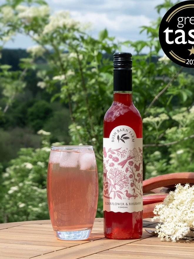 Elderflower & Rhubarb Cordial (Set Of 1, 2, 3 Or 4), a glass or cordial next to a bottle on a wooden surface. 