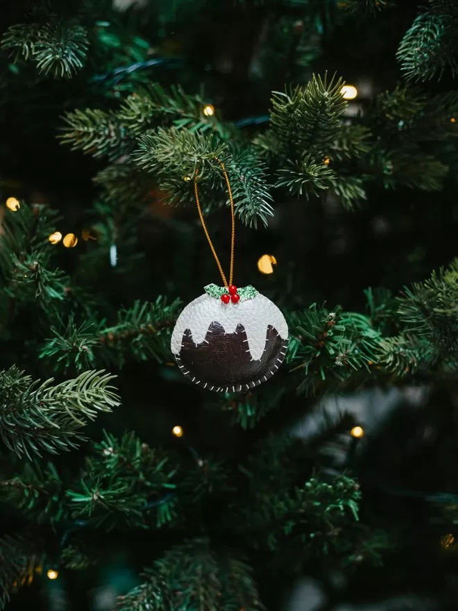 Hand stitched leatherette Christmas pudding decoration placed on a christmas tree