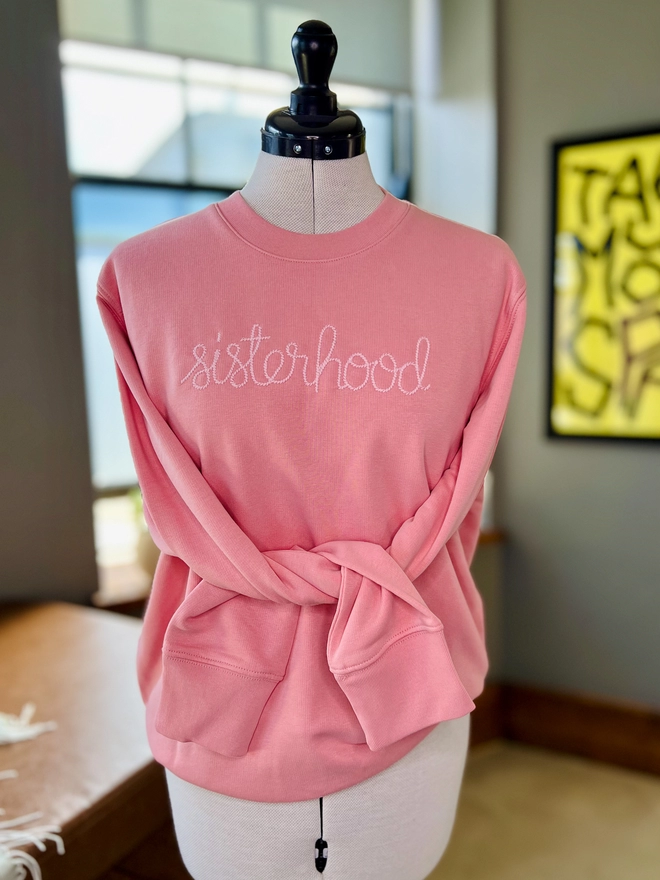 Pink sweatshirt embroidered with sisterhood on dressmakers dummy