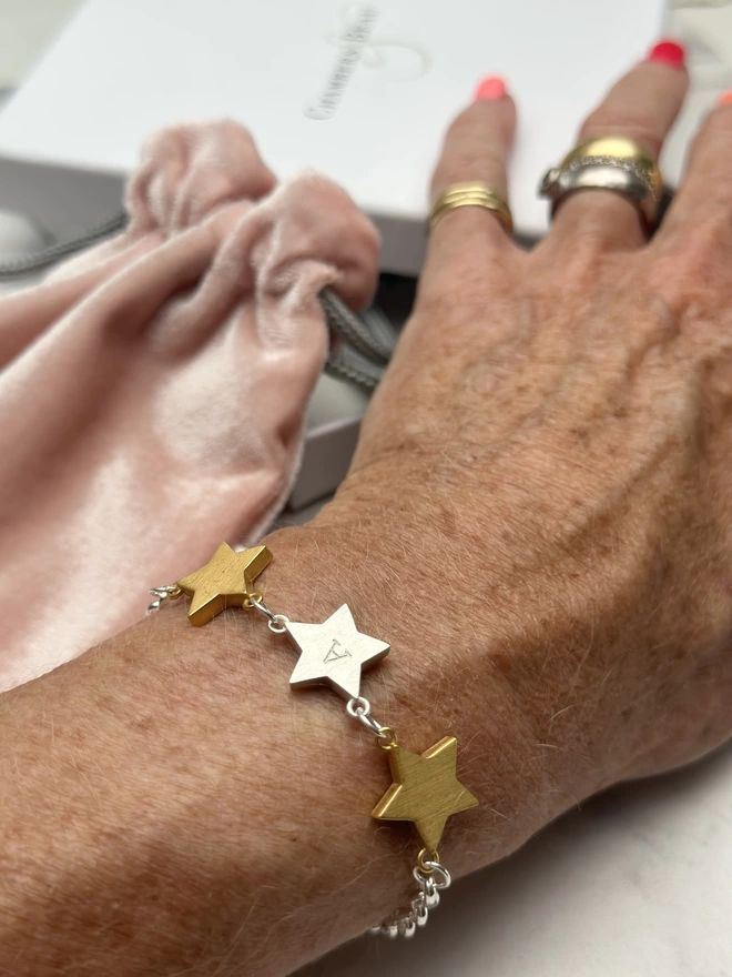 model wears sterling silver belcher chain bracelet with two chunky gold star charms either side of one personalised sterling silver star charm