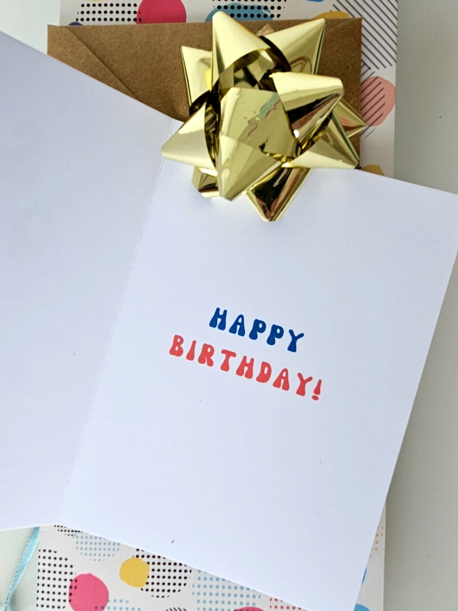 A photograph of the inside of a white card with green and red retro style text that says happy birthday.