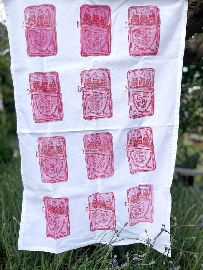 Pop of pink and red Sardine tea towel on garden background
