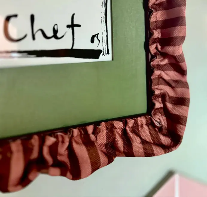 picture frame with red striped ruffled border framing green mount and picture