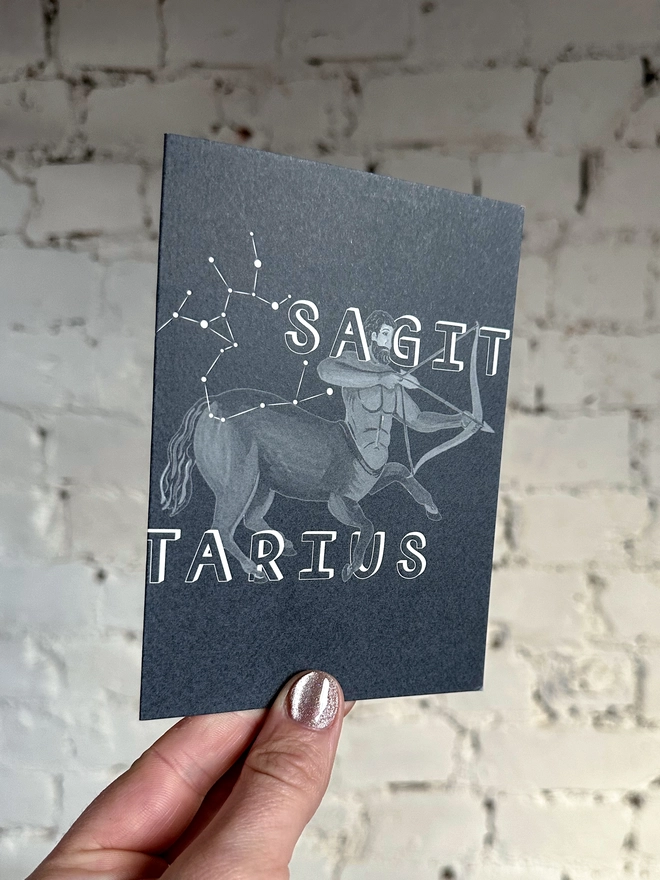a greetings card featuring a greyscale illustration of a zodiac style centaur with the text “SAGITARIUS”