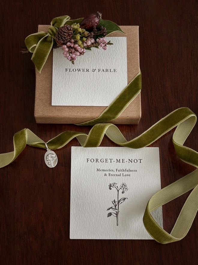 Forget me not medal charm on a green ribbon and gift box with flower posy