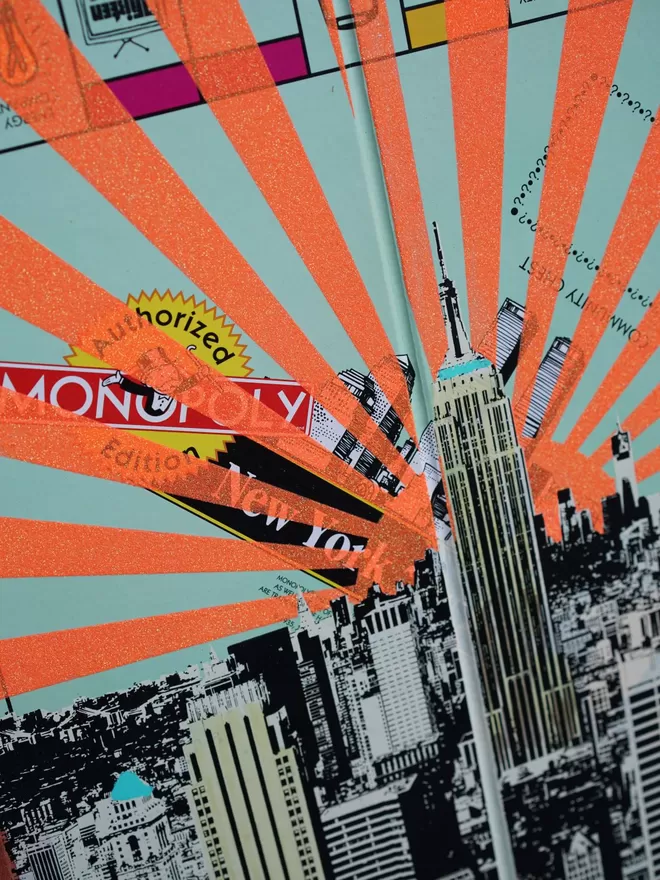 Close crop of a Monopoly Board with New York view printed on top with orange glitter stripes