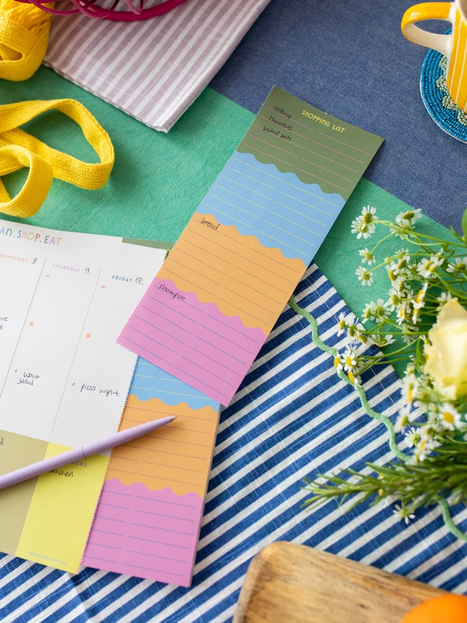 Colourful shopping list and weekly food planner lies on kitchen table