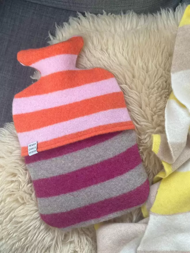 colourful stripy hot water bottle cover on sofa with blanket