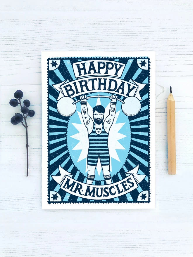 blue mr muscles muscle man card with dark berries and wood pencil