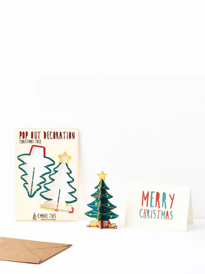 Pop out Christmas tree decoration and Merry Christmas card and brown kraft envelope on a white background