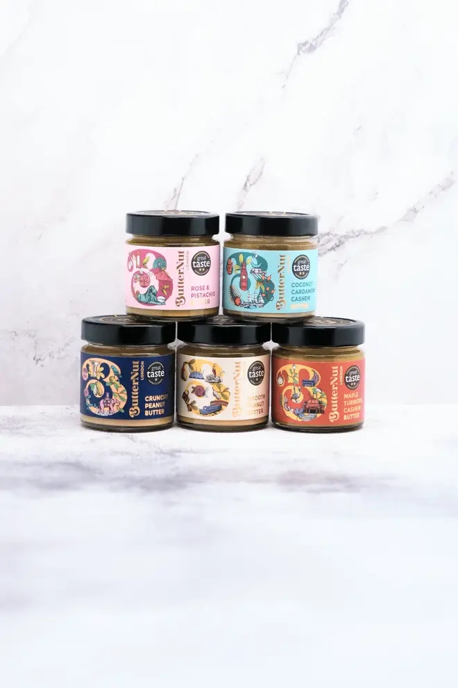great taste gift box. five jars of nut butter stacked on top of each other, photographed against a white marble backdrop.