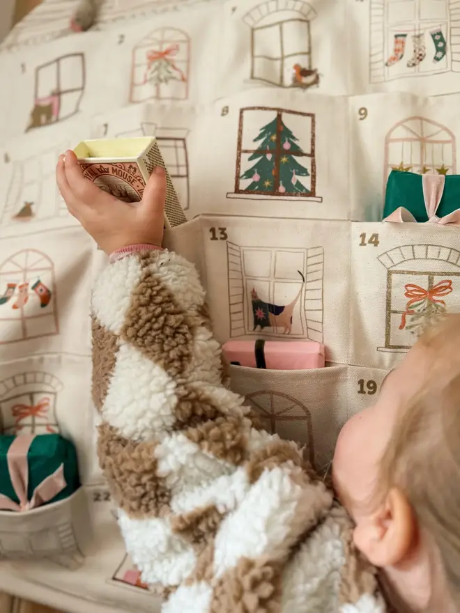 Fabric Christmas House Advent Calendar, with a little girl putting in a present. 
