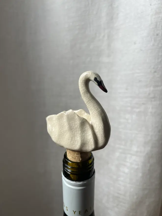 a ceramic, swan shaped bottle stopper, in a bottle of wine