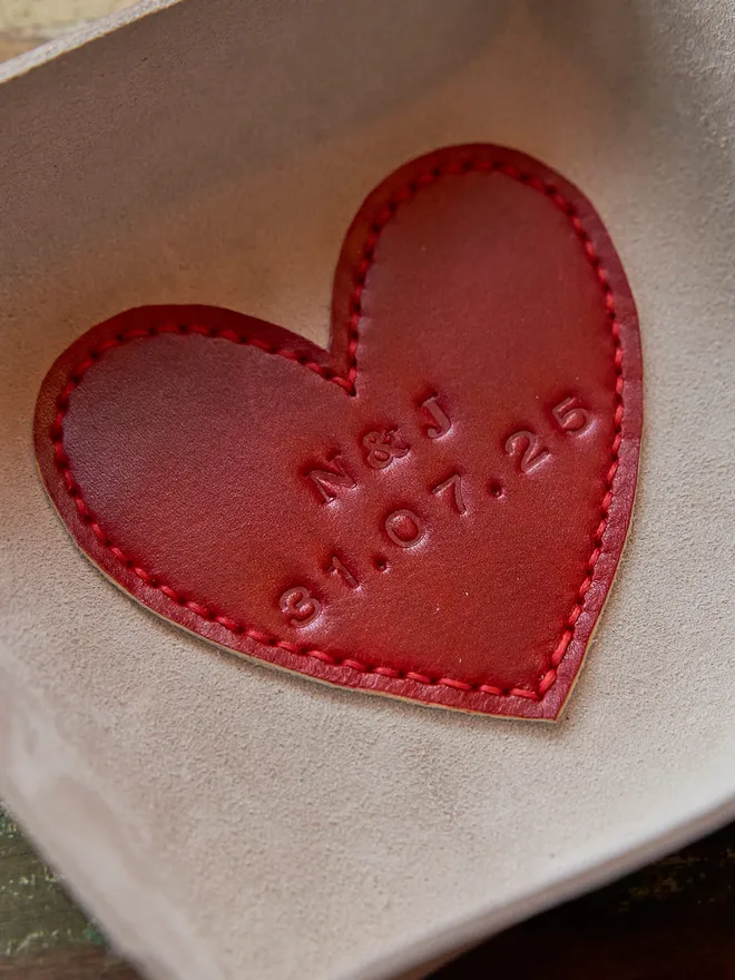 Personalised leather heart coin tray. Personalised leather heart coin tray. A natural cream square leather tray with a red leather heart stitched to the base. The heart is personalised with a couples initials and their wedding date.