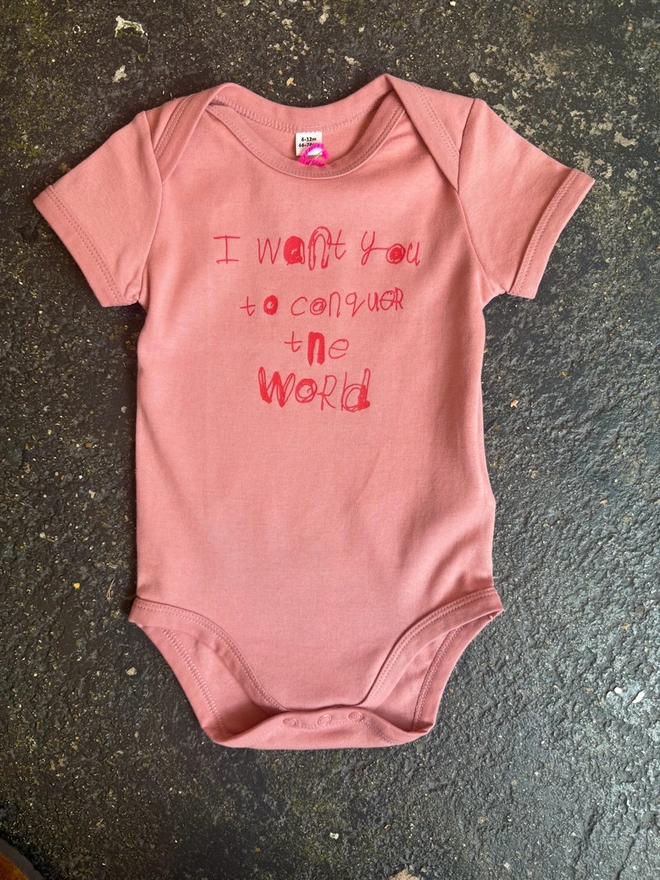 Pink baby grow with red font