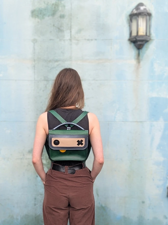 Green Robot backpack worn by model, front view.