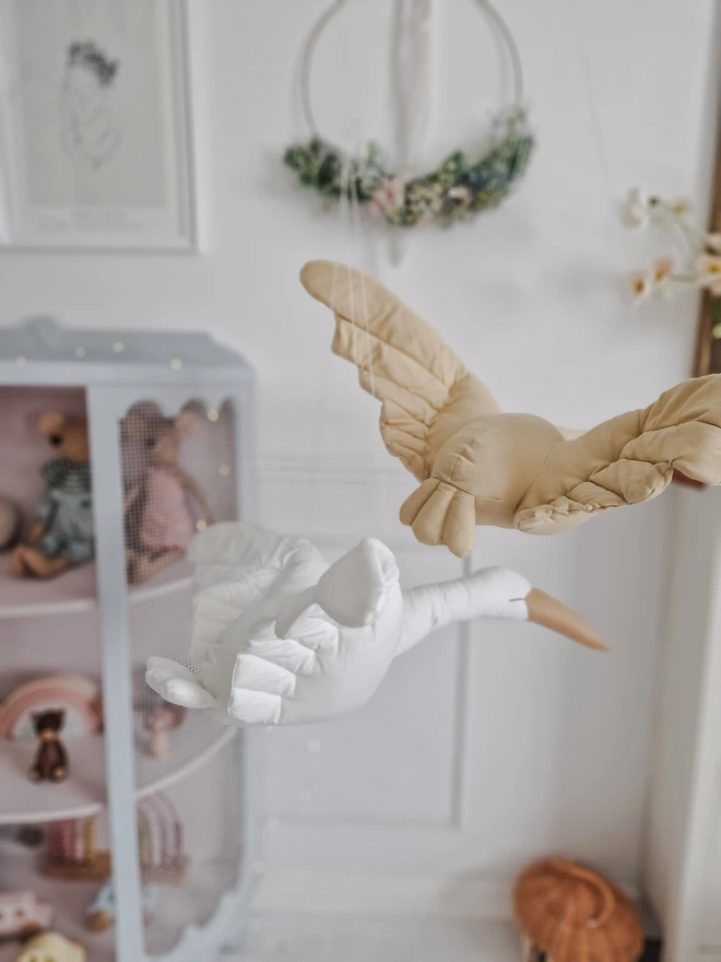 Flying Swan Hanging Decoration, a hanging beige swan decoration, suspended in a child's bedroom. 
