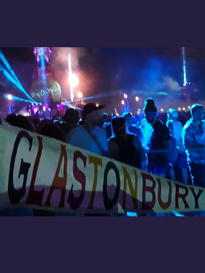 An ivory canvas Glastonbury pennant flag with multi coloured letters at the festival
