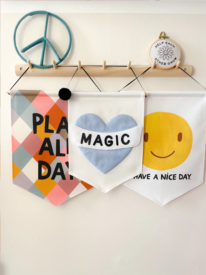 Three banners hanging on a wooden peg rail