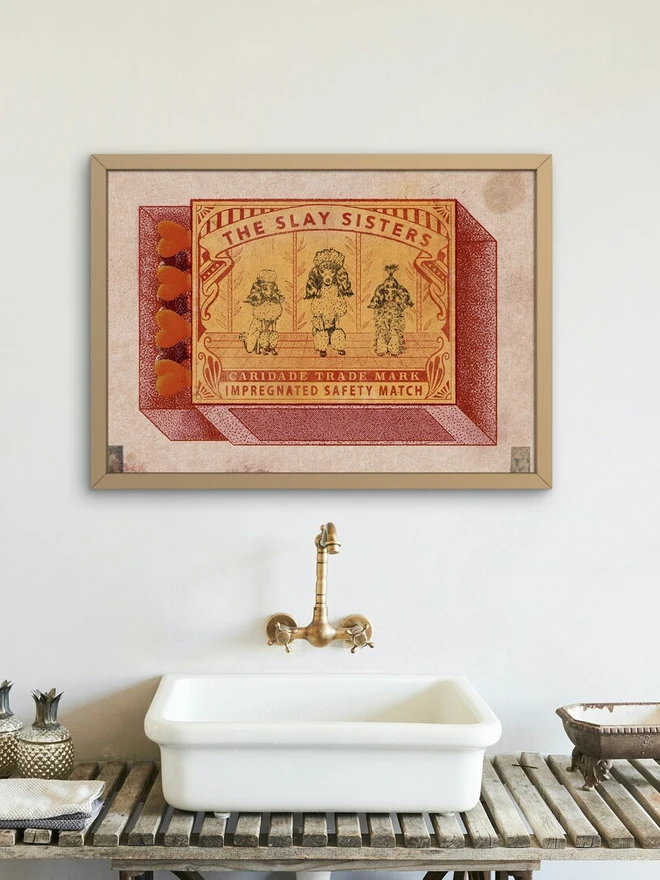 An illustrated image of a vintage matchbox. The matchbox is a faded golden yellow with red details. It features three poodles standing side-by-side. The poodles are highly stylized, with fluffy fur and topiary-like shapes. The poodle on the left has a puffball on its head, the middle poodle has a large, rounded bouffant, and the poodle on the right has its hair styled into a single upright spike. Above them, the text reads, "THE SLAY SISTERS," and below them, it says, "CARIDADE TRADE MARK IMPREGNATED SAFETY MATCH." The matches on the side of the box are a heart shape, and the entire image has a grainy texture, like it was screen-printed.