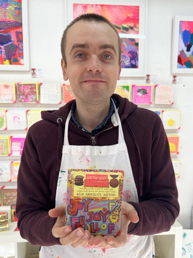 Happy artist holding colourful bag of charity full of joy milk chocolate buttons perfect for gifting