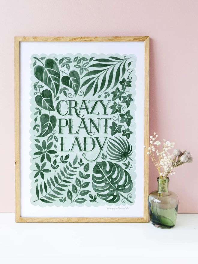 green and white crazy plant lady print in wood frame with pink background