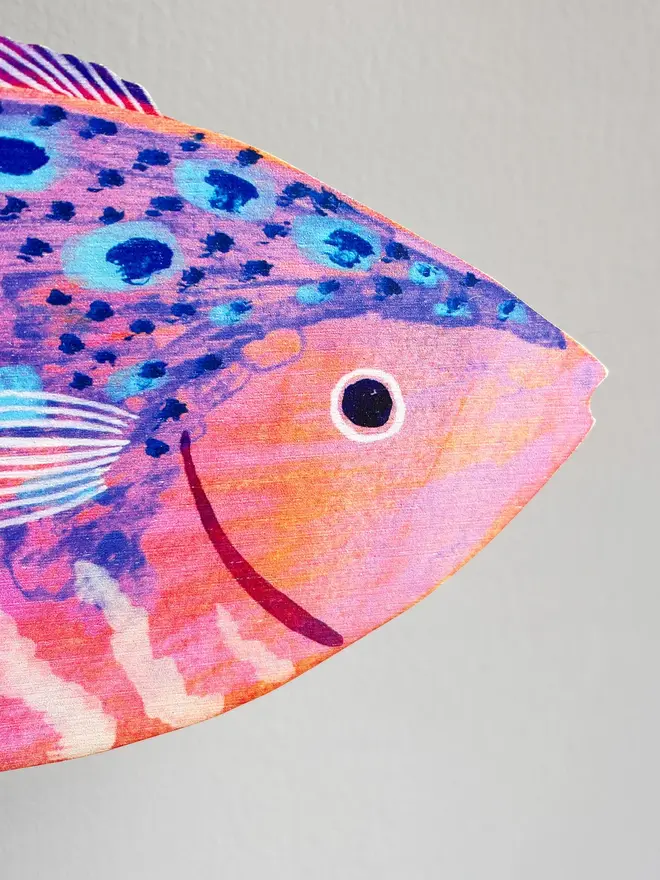 large wooden fish wall decoration. close up of wooden fish decoration hung on white wall.