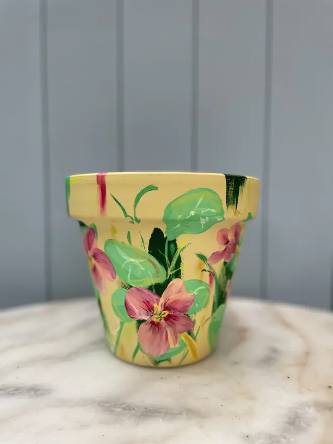 Unique hand-painted terracotta pot featuring apple blossoms on a pale blue background